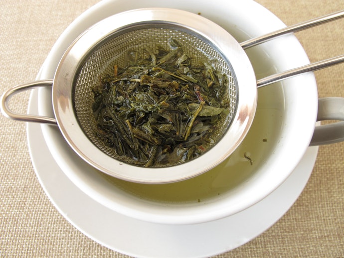 Seluruh daun teh terendam dalam air panas untuk teh hijau